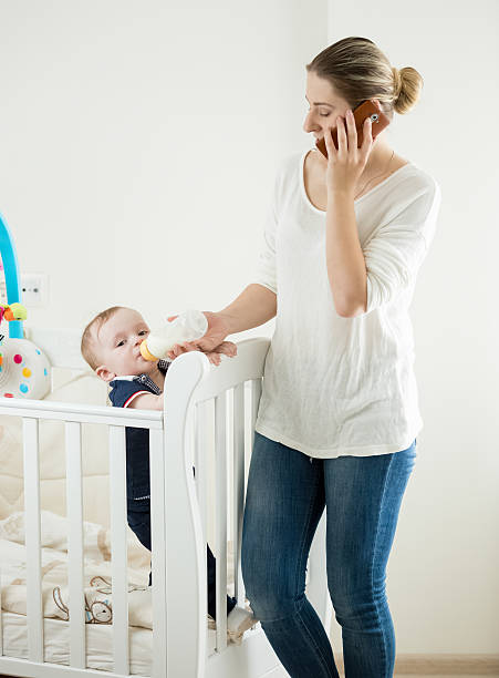 istock Woman working and talking by phone while feeding baby 613870468