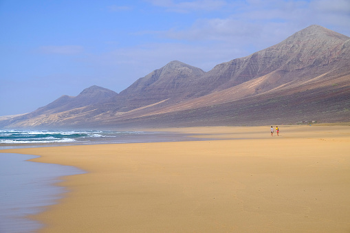 Wonderful view on the beach Cofete with couple walking along it. Location the Canary Island Fuerteventura, Spain.