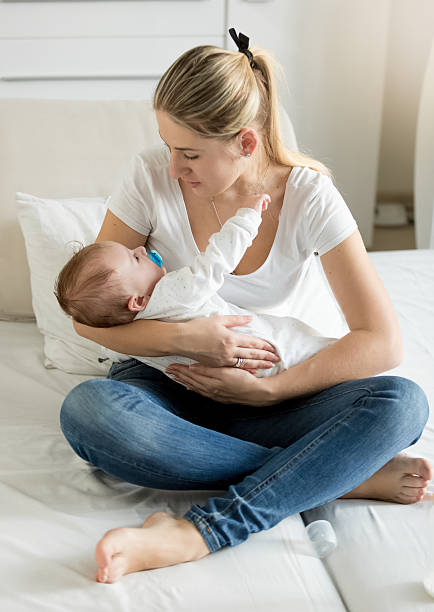 istock Mother sitting on bed with her 3 months old baby 613873252