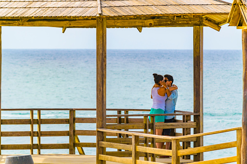 Salinas, Ecuador - October 22, 2015: Young couple kissing at gazebo in La chocolatera, a famous nature viewpoint towars the pacific ocean in Salinas, Ecuador