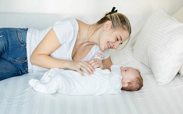 istock Smiling mother playing on bed with her cute baby boy 613873698
