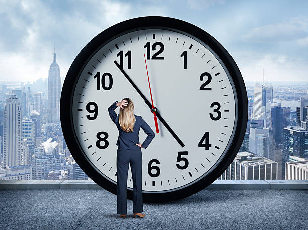 istock Businesswoman Looking Up At Large Clock 613876360