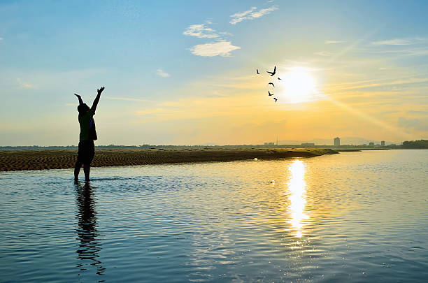 istock Silhouette of Man Raising His Hands  when sunset 613880074