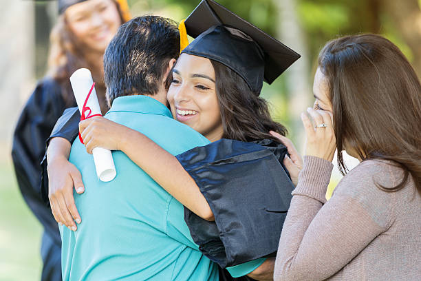 istock College graduate hugs dad while mom watches proudly 613884704