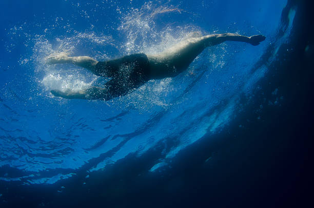 istock Man swimming underwater across clear water 613886312