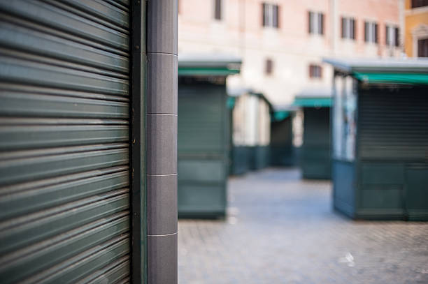 istock Closed stall shop in urban street rolling shutter close up 613886436