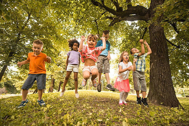 Large group of playful children jumping in the park and having fun together.