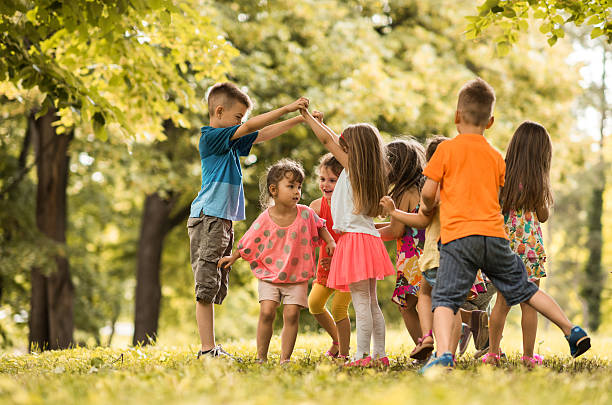 istock Large group of small children having fun while playing outdoors. 613891794