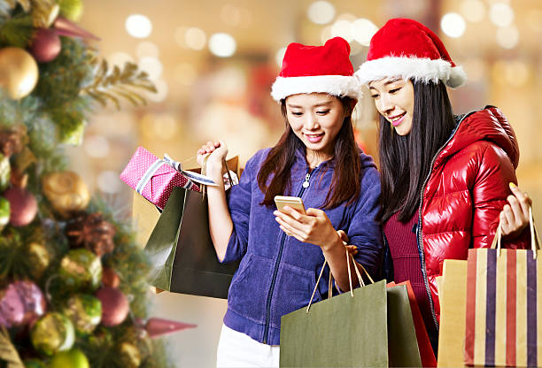 young asian women using cellphone during christmas shopping