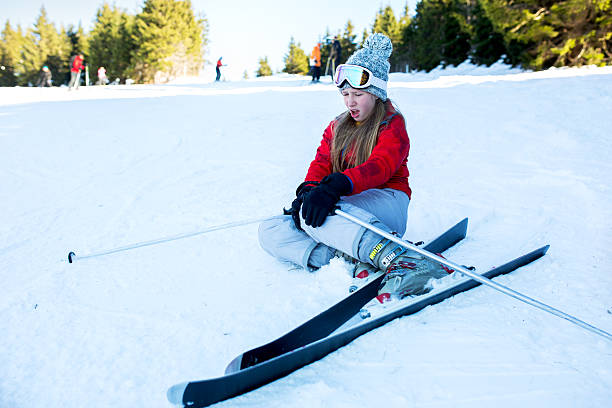 adolescente blessée sur la neige, tenant sa jambe dans la douleur. - skiing teenager ski wear winter photos et images de collection