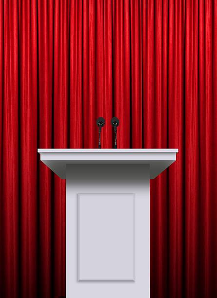 istock White podium over red curtain background 613893132