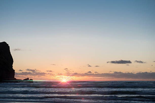 istock Beautiful sunset on Piha beach with flare 613893630
