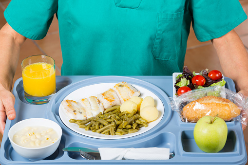 Health professional with a tray of food to a patient