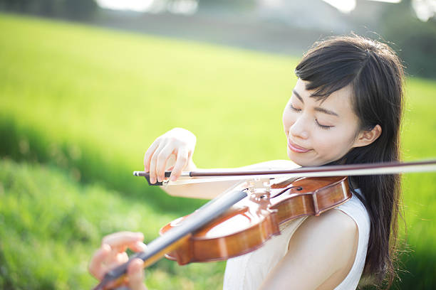 istock Woman playing the violin in a rice paddy 613896074
