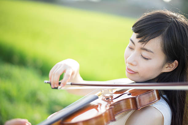 istock Woman playing the violin in a rice paddy 613896172