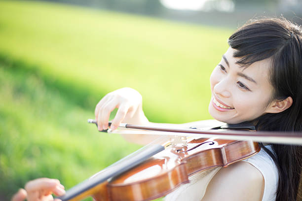 istock Woman playing the violin in a rice paddy 613896246