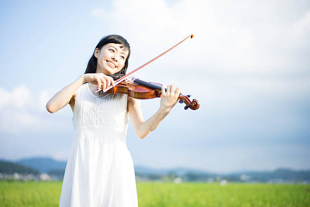 Woman playing the violin in a rice paddy