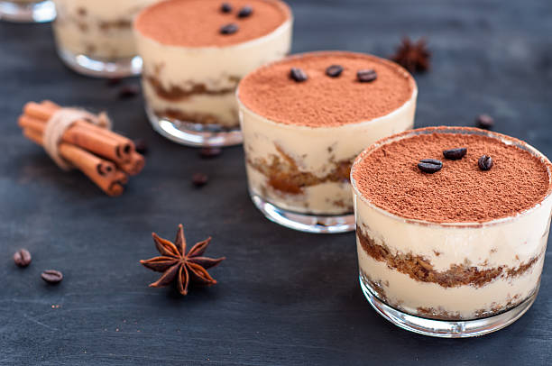 tiramisu in a glass on a dark background tiramisu in a glass tiramisu in a glass decorated with coffee beans on a dark background tiramisu glass stock pictures, royalty-free photos & images