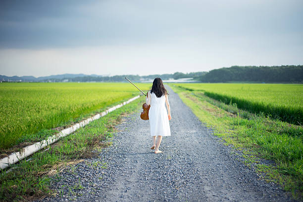 Female hiker is walking on footpath through summer meadow