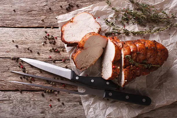 rustic food: roasted turkey breast on a paper on the table. horizontal top view