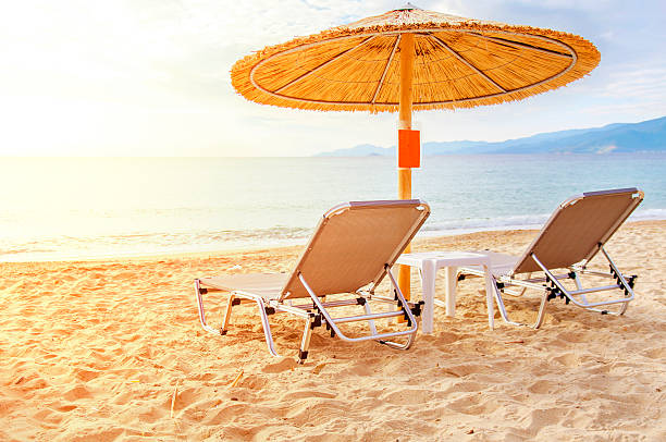 istock Gray straw umbrella on beach and ocean with burning sun 613900494
