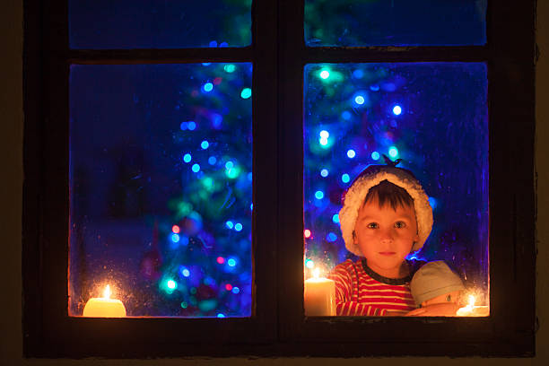 istock Cute little boy, sitting on a window at night 613900746