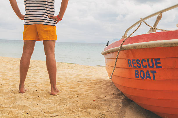 Lifeguard posing with his boat on the beach.