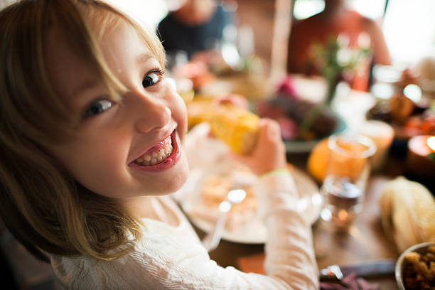 istock Little Girl Eating Corn Thanksgiving Celebration Concept 613904934