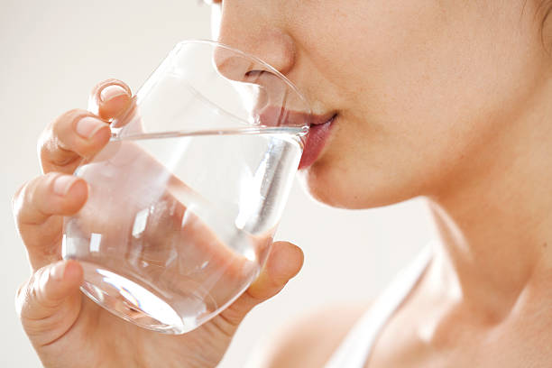 jovem mulher beber água de vidro - bebida imagens e fotografias de stock