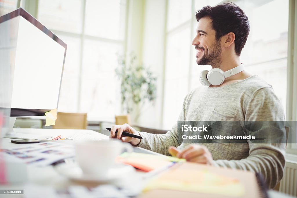 Smiling businessman working on computer in office Young smiling businessman working on computer in creative office Adult Stock Photo