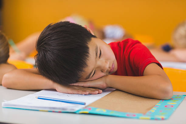 istock Schoolboy lying on desk in classroom 614013558