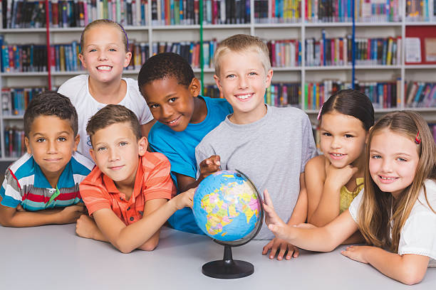 istock Portrait of school kids looking at globe in library 614013738