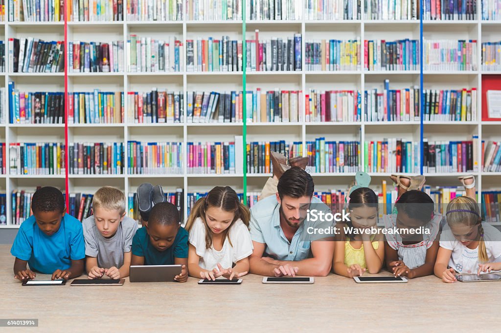 Professor e crianças deitados no chão usando tablet digital - Foto de stock de Educação royalty-free