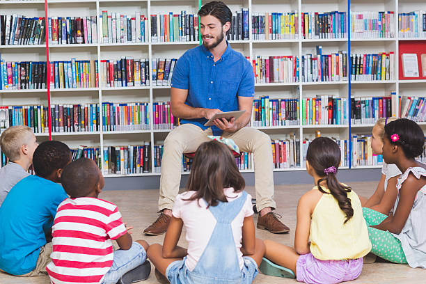 istock Teacher teaching kids on digital tablet in library 614014004