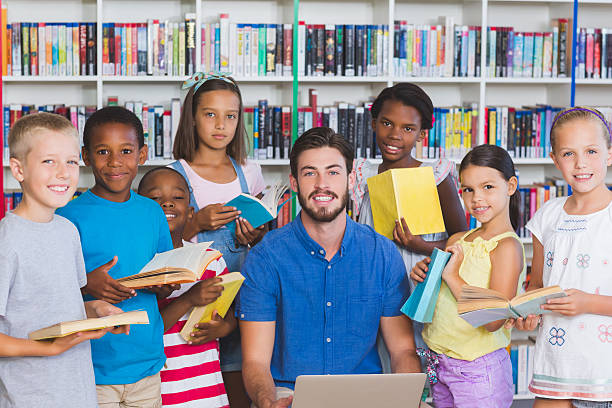 istock Teacher teaching kids on laptop in library 614014152