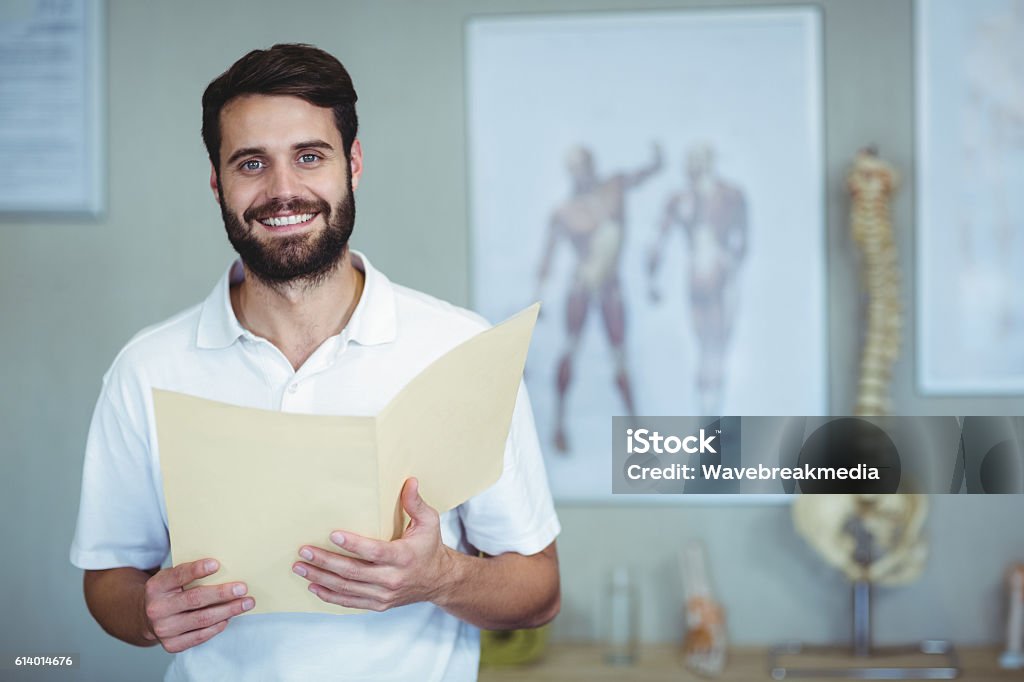 Portrait of physiotherapist holding file Portrait of smiling physiotherapist holding file in clinic Osteopath Stock Photo