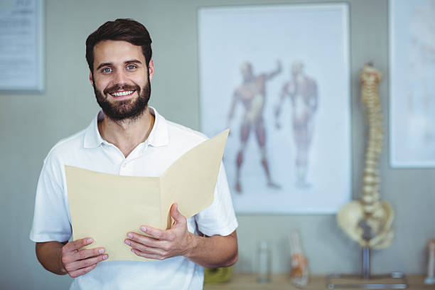 Portrait of physiotherapist holding file Portrait of smiling physiotherapist holding file in clinic osteopath photos stock pictures, royalty-free photos & images