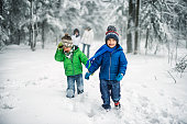 Little brothers with family enjoying winter walk in forest.
