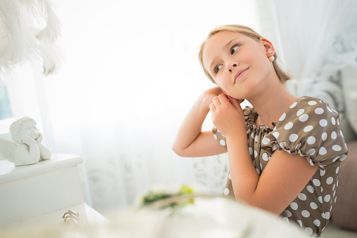 7 or 8 years old little girl with blond hair posing pointing with earrings