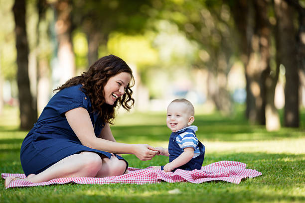 Mother playing with cute baby outdoors.