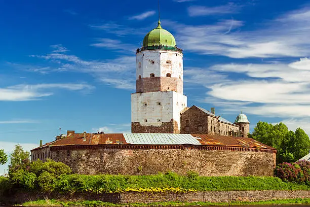 Vyborg castle on island. Medieval Swedish fortress on Gulf of Finland is tourist attraction in Leningrad region, Saint-Petersburg, Russia. Restored stone walls surrounded by green trees, island is washed by Gulf of Vyborg