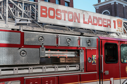 Boston, MA, USA - September 26 2016: Fire department engine seen returning from an incident in downtown Boston, MA. Detail of the side of the vehicle can clearly be seen including the ladder at the top of the engine and various stowage compartments at the side of the vehicle.