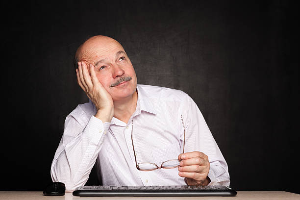 istock elderly man at work dreamily looks away during a break. 614025092