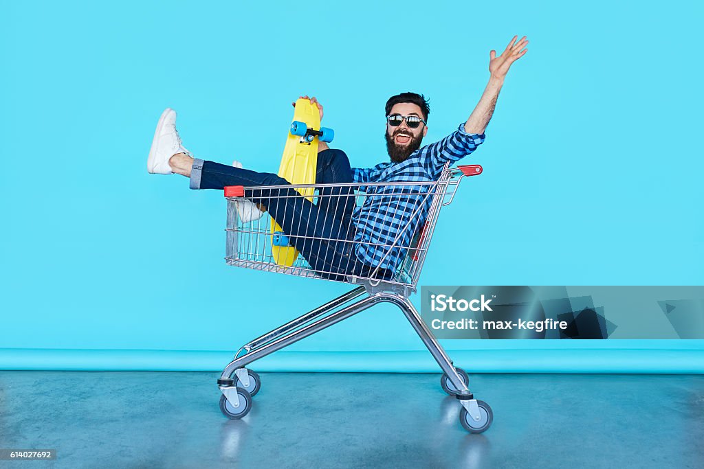 beau jeune hipster assis dans le panier - Photo de Caddie libre de droits