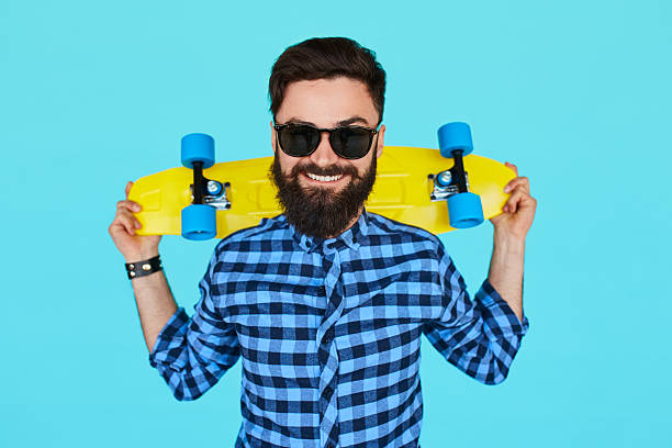 istock hipster man holding a bright vibrant yellow skateboard 614027800