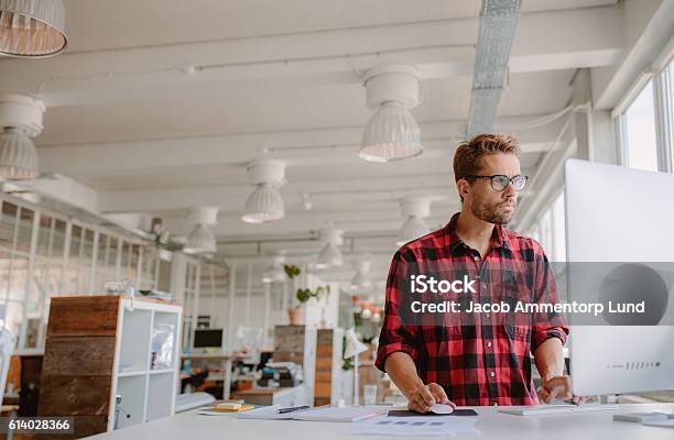 Young Man Working On Computer In Modern Workplace Stock Photo - Download Image Now - Office, Small Business, Owner