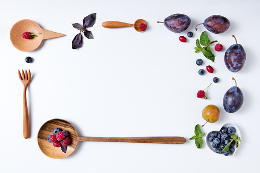 Plums and wooden spoons on a white background
