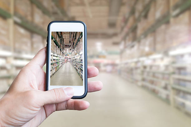 istock Hand holding smartphone with supermarket background 614032236
