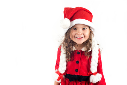 Little girl in santa claus costume is looking at camera.