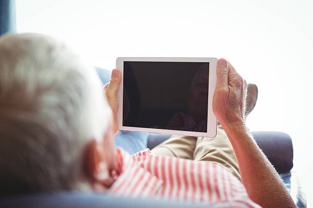 istock Lying on a couch senior man looking at digital tablet 614035290